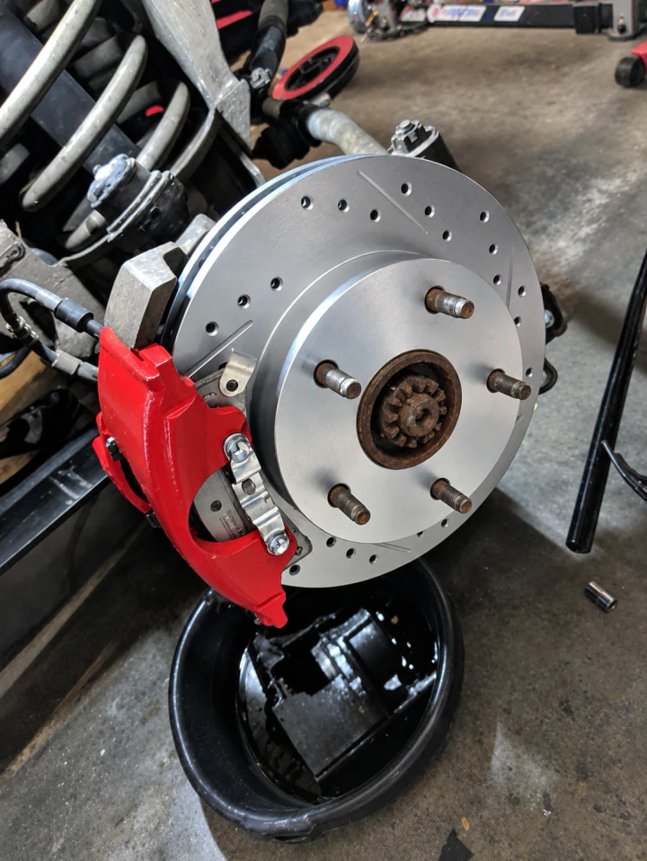 A new drilled and slotted brake rotor with a red caliper, installed on a vehicle